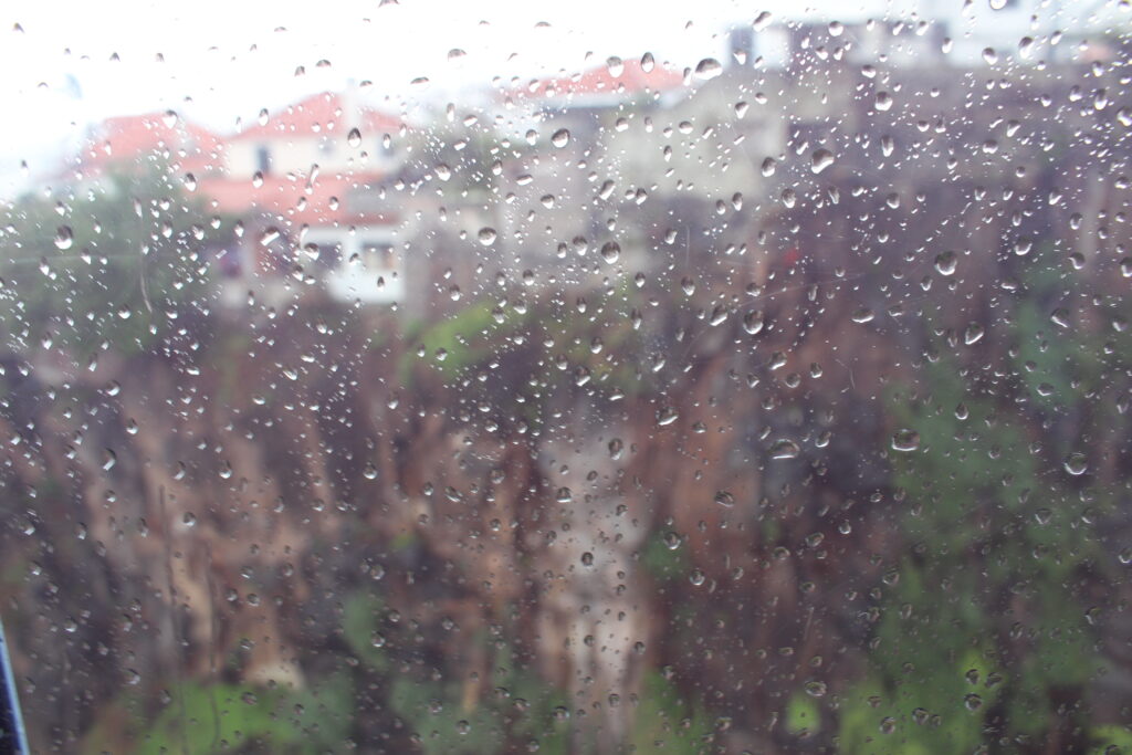 Widok przez mokrą od deszczu szybę wagonika